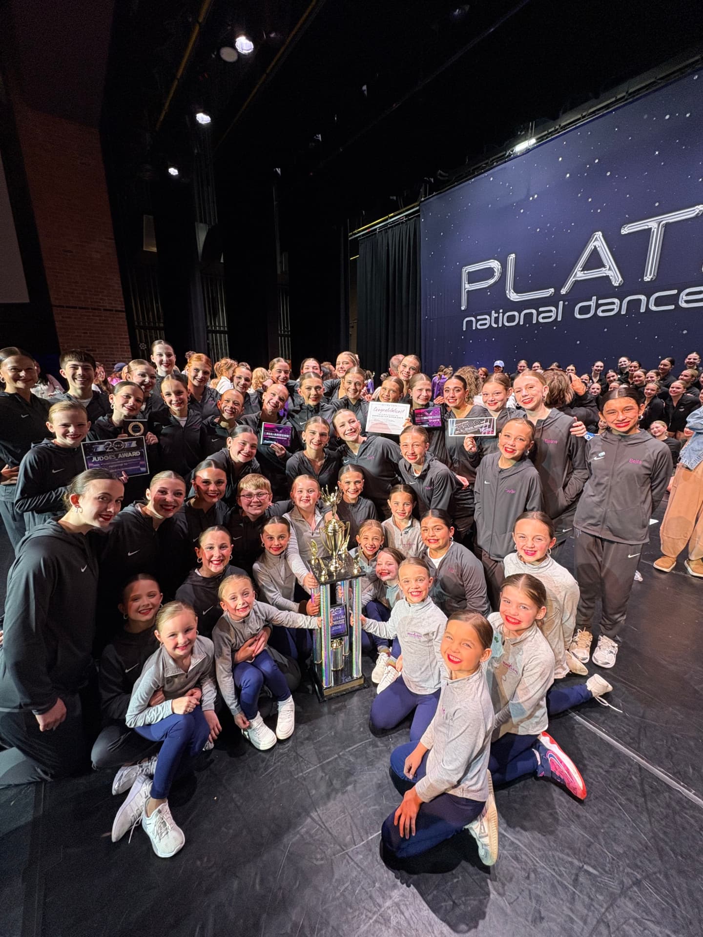 Next Level competition team posing with a large trophy at Platinum National Dance Competition