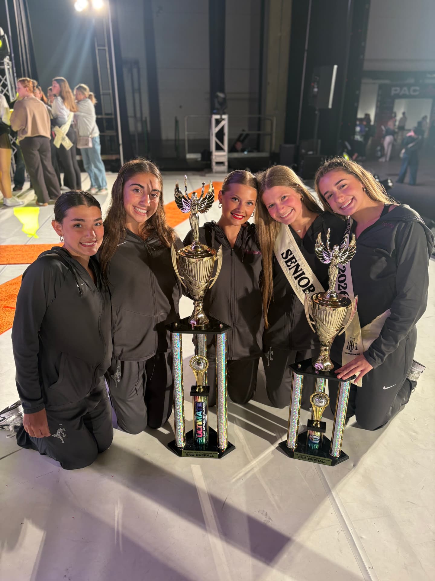 Next Level dancers kneeling with second and third overall trophies